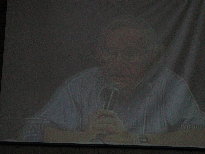 Marc's view of Noam Chomsky on a video screen in a remote location with a Portuguese over-dub